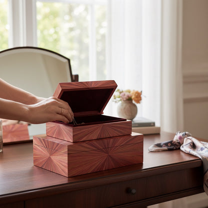 Kra Design luxury handcrafted jewelry box with straw marquetry sunburst pattern, dark red interior, on a wooden desk.