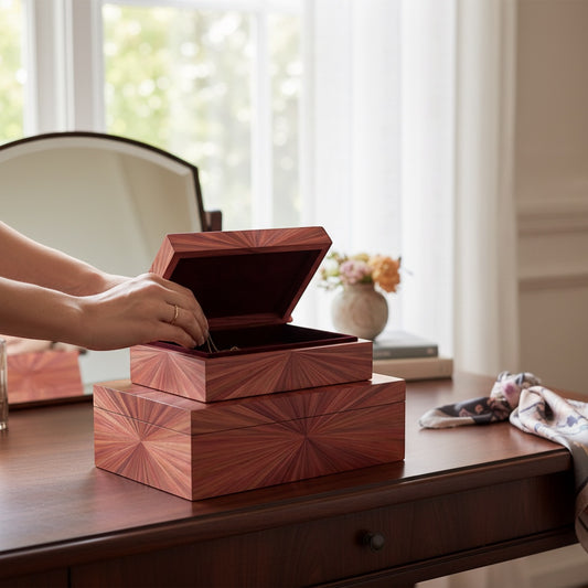 Kra Design luxury handcrafted jewelry box with straw marquetry sunburst pattern, dark red interior, on a wooden desk.