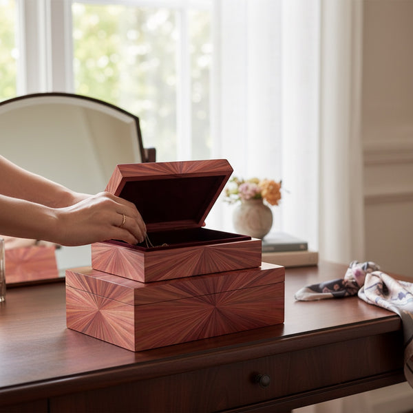 Kra Design luxury handcrafted jewelry box with straw marquetry sunburst pattern, dark red interior, on a wooden desk.